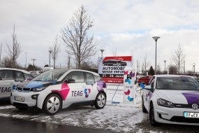 Bild: Ein BMW i3 und VW e-Golf im TEAG-Design auf dem Gelände der TEAG-Hauptverwaltung. Im Hintergrund ein Plakat zur Automobilmesse Erfurt