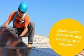 Bild: Ein Monteur der KomSolar bringt Solarmodule auf einem Dach an